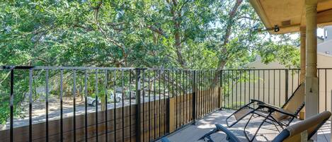 A balcony with a view of trees and a fence.