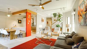 A modern living room with a sofa, chairs, a glass coffee table, and a red carpet.