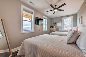 A bedroom with two beds, a ceiling fan, a TV mounted on the wall, and large windows. - Scenic Hillside Cabin in Sylva w/ Hot Tub & Views! (Sylva)