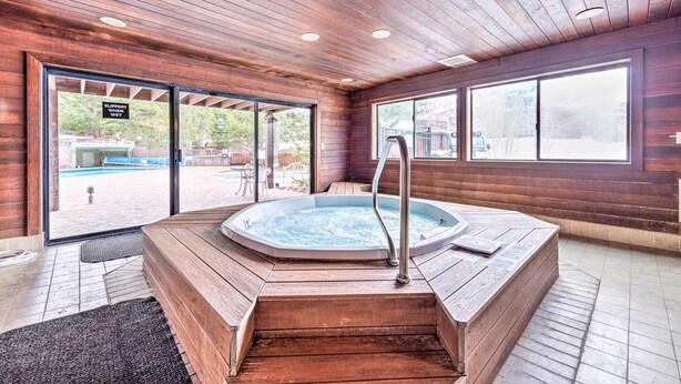 A wooden-floored spa area with a hot tub, large windows, and a view of an outdoor pool. - Renovated Park City Condo: Hike, Bike & Ski! (Park City)
