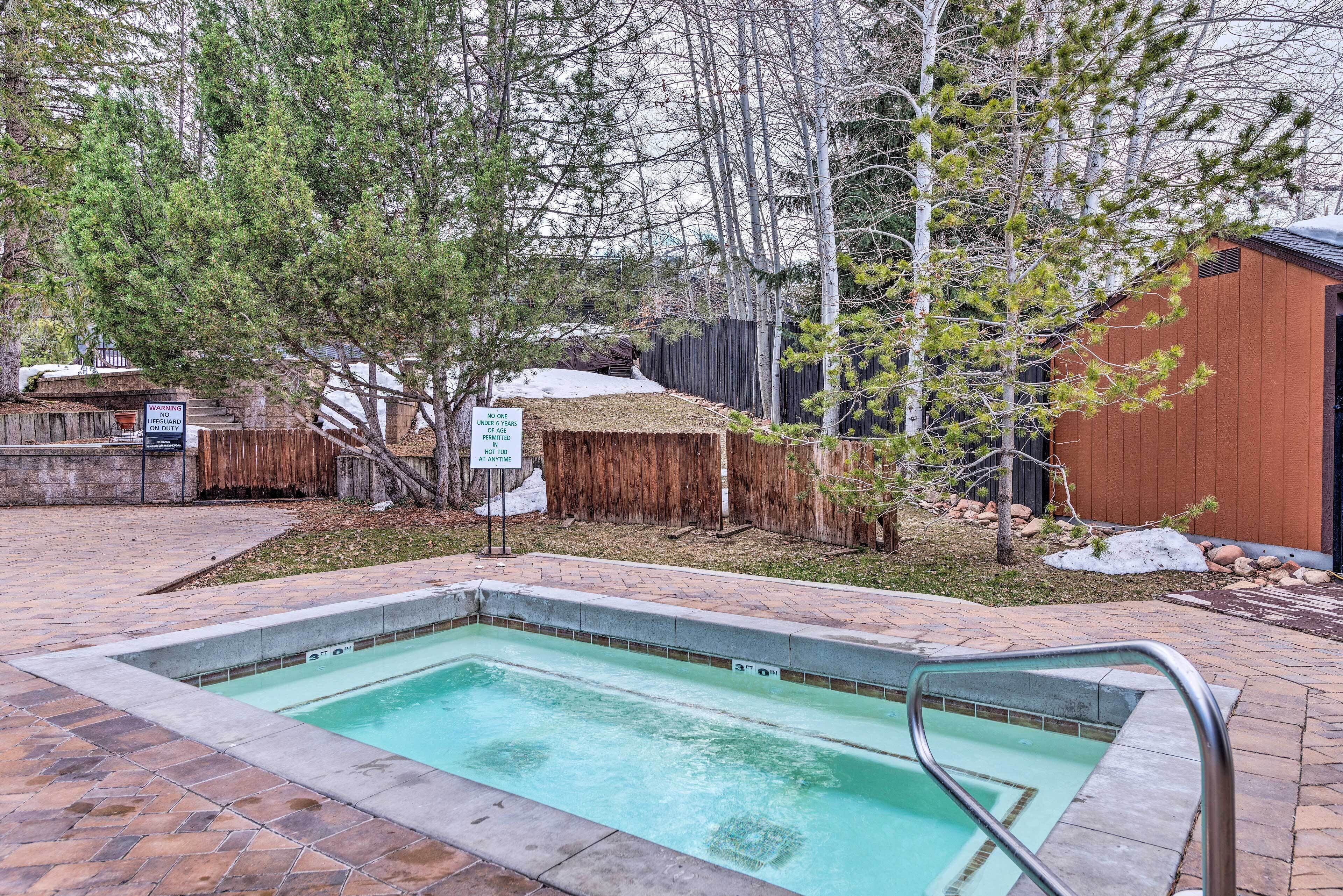 A rectangular pool with a stone border, surrounded by a wooden fence and trees.