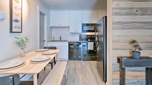 A modern kitchen with white cabinets, stainless steel appliances, and a wooden accent wall. - Renovated Park City Condo: Hike, Bike & Ski! (Park City)