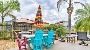An outdoor patio with a grill, a table with chairs, and a colorful umbrella. - Pet-friendly Hudson Home: Boat Slip, Private Pool (Hudson)