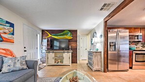 A modern living room with a flat-screen TV, a wooden accent wall, and a kitchen area with a stainless steel refrigerator and microwave. - Pet-friendly Hudson Home: Boat Slip, Private Pool (Hudson)