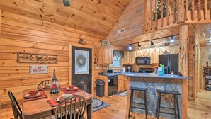 A wooden cabin interior with a dining area, kitchen, and a stone bar. - Rural Murphy Cabin - Yard, Hot Tub & Fire Pit (Murphy)