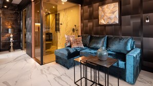 A modern living room with a blue velvet sofa, a marble floor, and a geometric wall art piece. - Art Suites Luxury Hotel (Kraków)