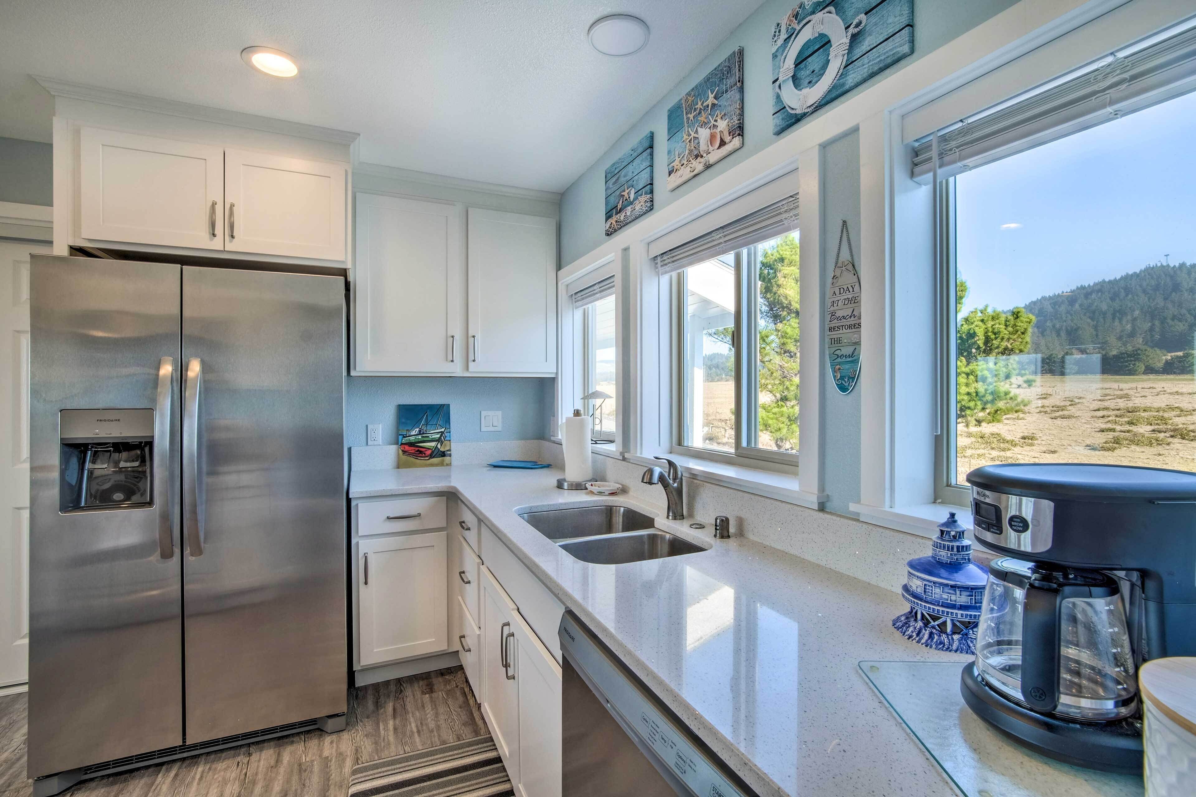 A modern kitchen with stainless steel appliances, white cabinetry, and a large window offering a view of the outdoors.