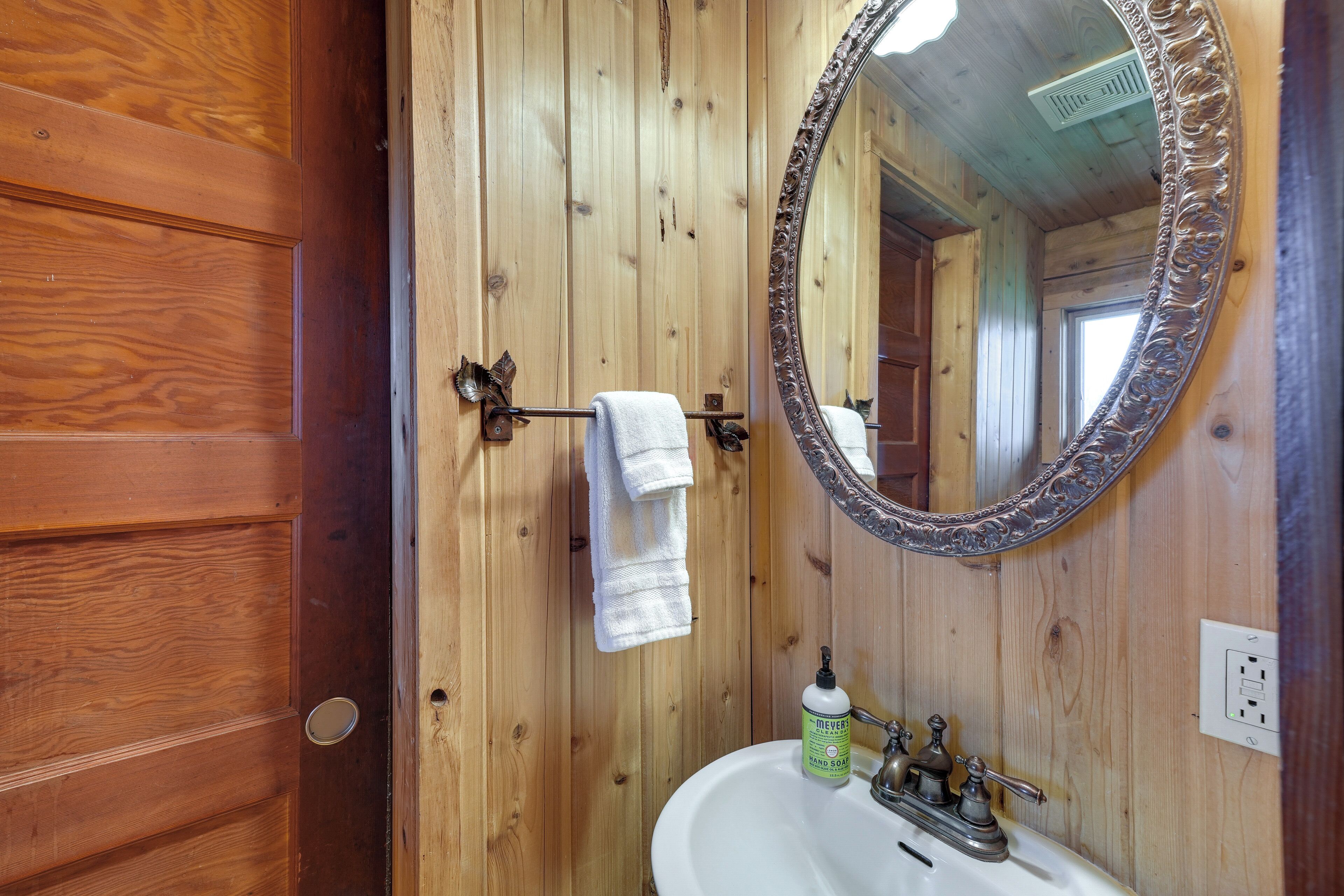 A wooden bathroom with a white sink, a mirror, and a towel rack.