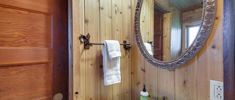 A wooden bathroom with a white sink, a mirror, and a towel rack.