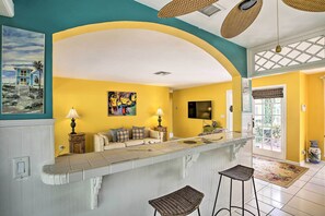 A kitchen with a curved island, yellow walls, and a large window. - Cape Coral Home w/ Yard < 1 Mi to Dtwn! (Cape Coral)