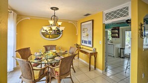 A dining area with a round table, wicker chairs, and a chandelier. - Cape Coral Home w/ Yard < 1 Mi to Dtwn! (Cape Coral)
