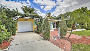 A residential property with a garage, a brick pathway, and lush greenery including palm trees and various plants. - Cape Coral Home w/ Yard < 1 Mi to Dtwn! (Cape Coral)