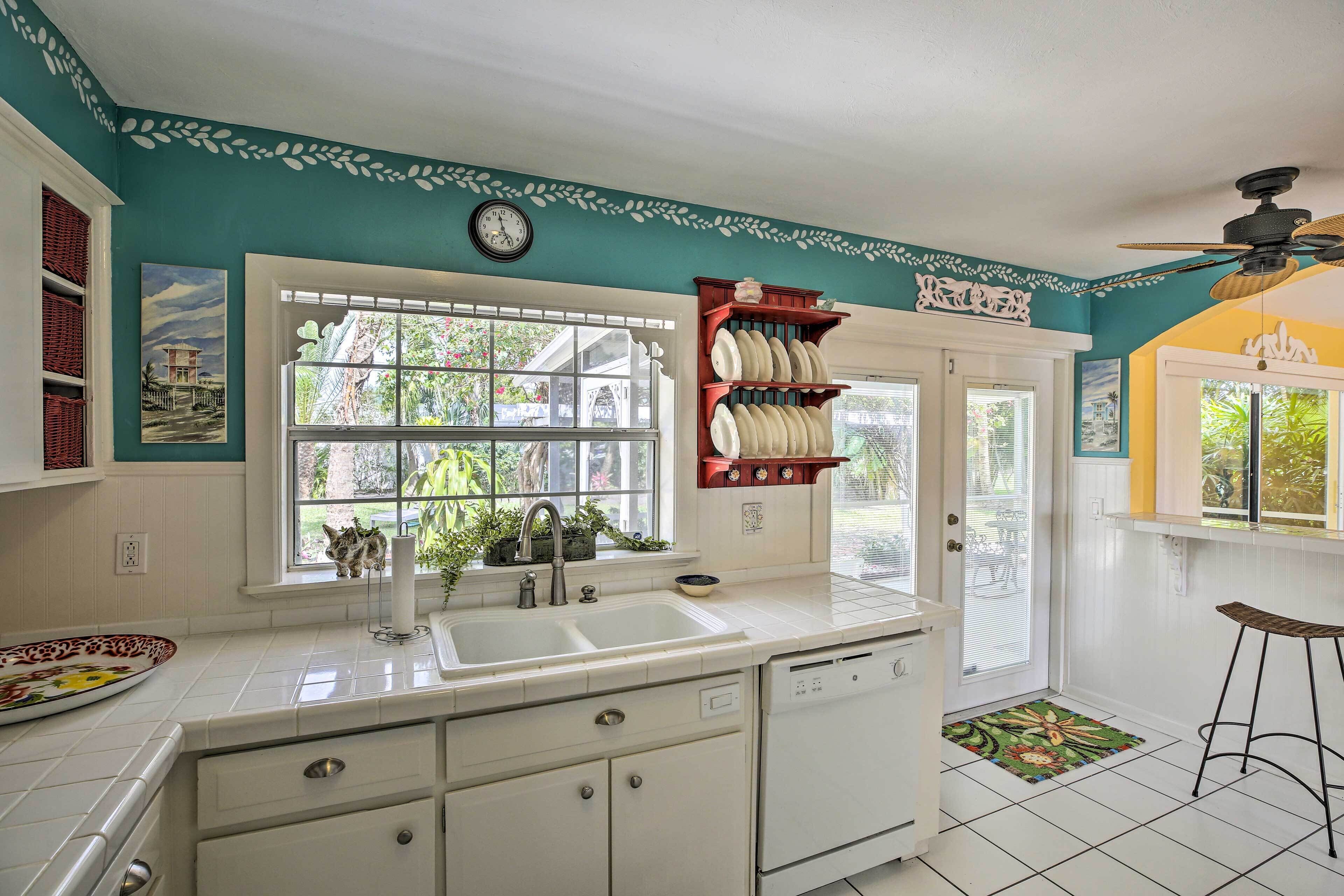 A kitchen with a large window, white cabinets, and a dish rack.