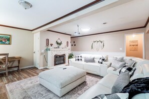 A living room with a fireplace, white sofa, and a dining area with a wooden table and chairs.