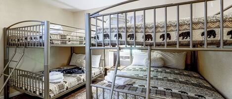 A bunk bed room with metal railings and patterned bedding.