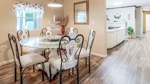 A dining area with a round glass table surrounded by chairs, a chandelier, and a window with curtains. - Pool Open Until Oct 15th! ~ 1 Mi to Dollywood (Pigeon Forge)