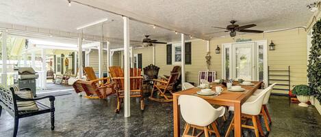 An indoor dining area with a high ceiling, wooden chairs, a table set for four, and a ceiling fan.