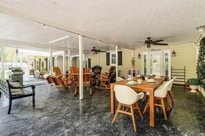 Un comedor interior con techo alto, sillas de madera, una mesa dispuesta para cuatro personas y un ventilador de techo.
