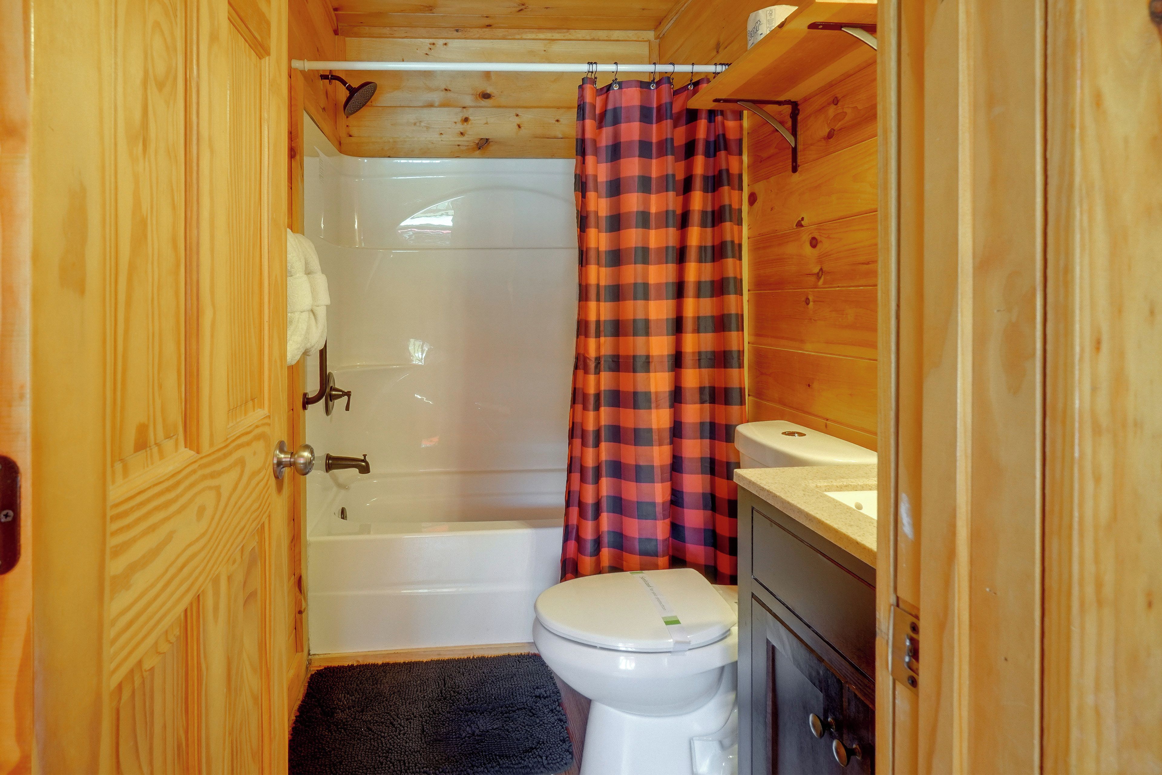 Een kleine badkamer van hout met een bad, toilet en wastafel.