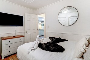 Un dormitorio con una cama, un aparador, un televisor y un espejo.