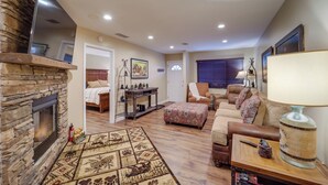 A living room with a stone fireplace, a sofa set, a coffee table, and a lamp. - Mtn-view Condo w/ Lookout Deck in Banner Elk! (Banner Elk)