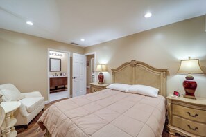 Een slaapkamer met een groot bed, nachtkastjes, een nachtlampje en een deur naar een badkamer.