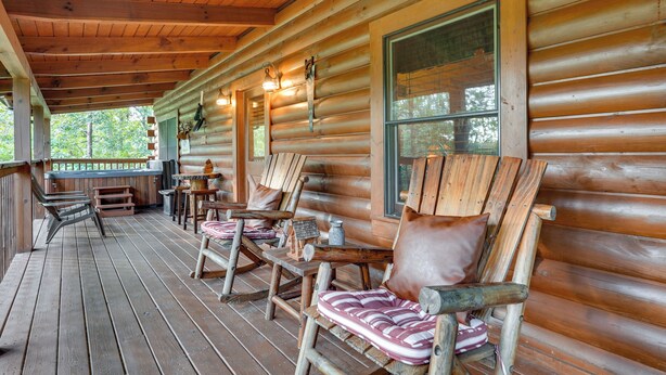 A log cabin with a porch featuring wooden chairs and a table. - The Dreamer's Nest Sevierville Cabin w/ Hot Tub! (Sevierville)