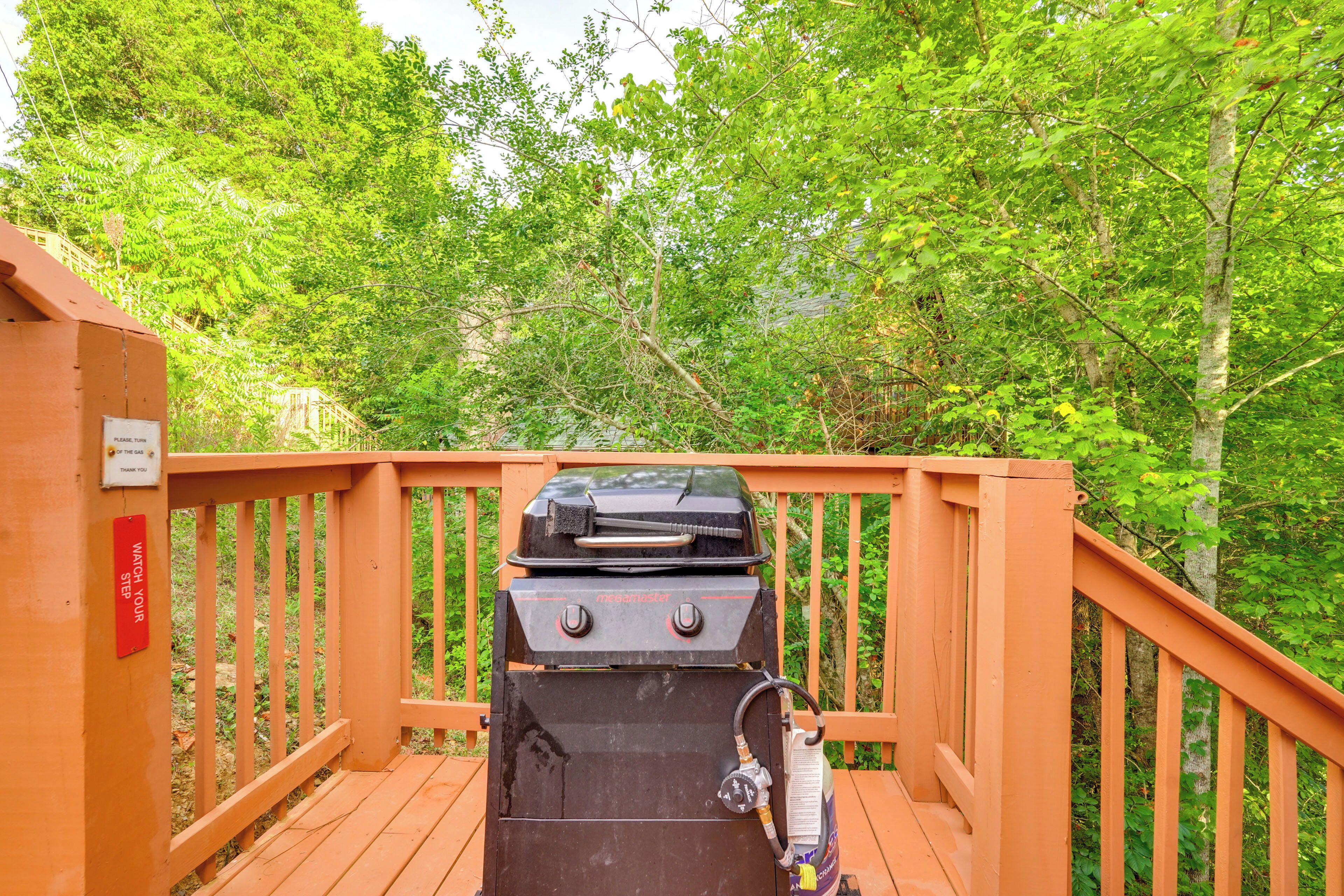 Ein Grill auf einer Holzterrasse, umgeben von üppigem Grün.