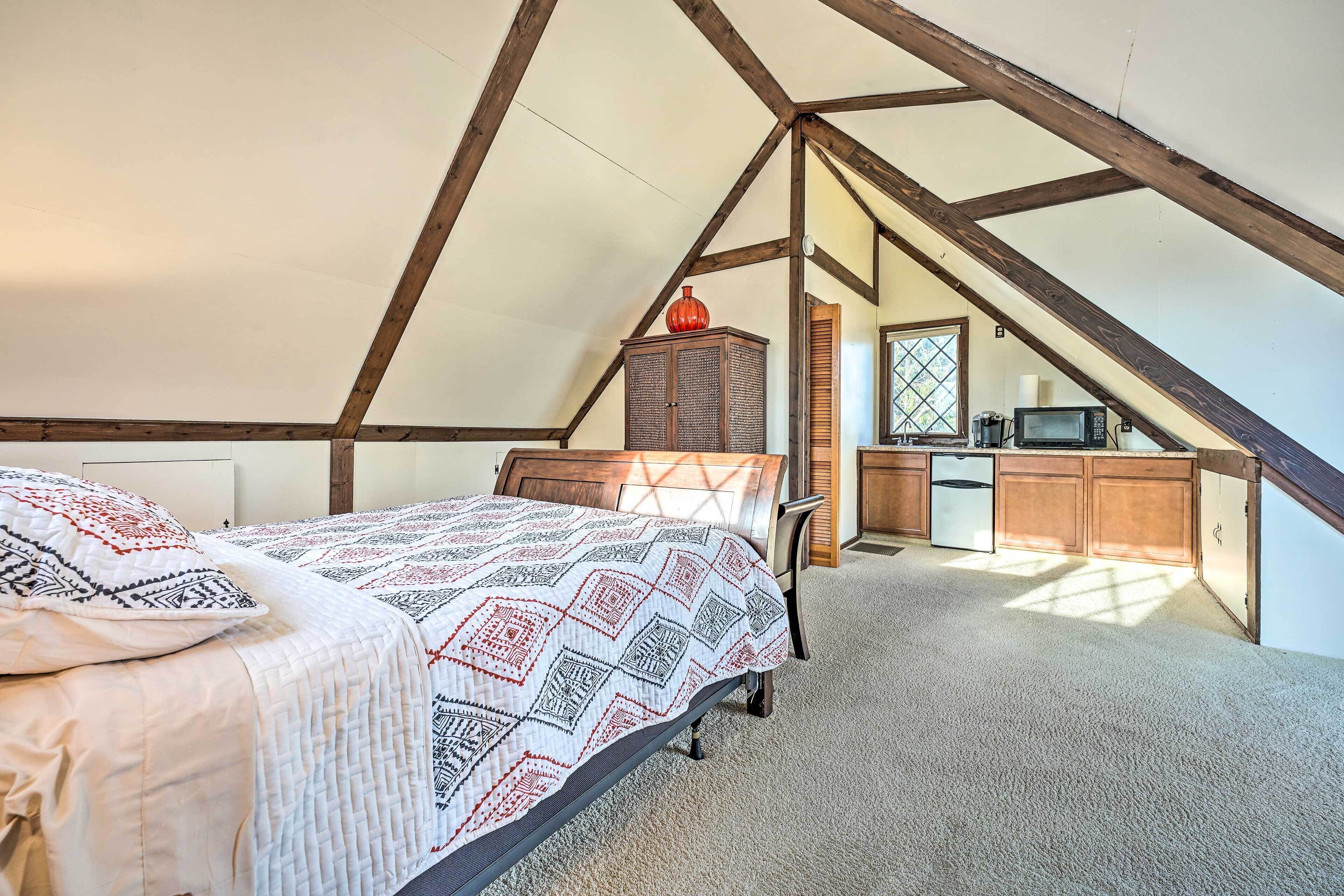 A bedroom with a bed, a wooden cabinet, a microwave, and a window.