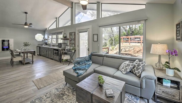 A spacious living area with a large sofa, a coffee table, and a dining table. There is a kitchen in the background with a dining area. - Shingle Springs Escape w/ Pool Near Casino! (Shingle Springs)