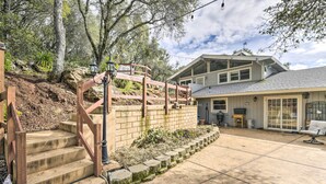 A house with a stone staircase, a covered patio, and a large window overlooking a garden. - Shingle Springs Escape w/ Pool Near Casino! (Shingle Springs)