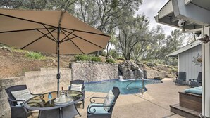 An outdoor pool area with lounge chairs, a table with drinks, and a large umbrella. - Shingle Springs Escape w/ Pool Near Casino! (Shingle Springs)