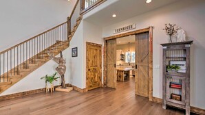Un escalier en bois menant à une mezzanine, une porte en bois rustique portant l’inscription « FERME », et un petit meuble en bois sur lequel est posé un panneau d’accueil.