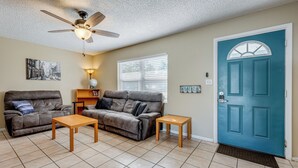 A living room with two sofas, a coffee table, a ceiling fan, a door, and a window with blinds. - Fire Pit! Family Getaway, 6 Mi to Beach Access (Largo)