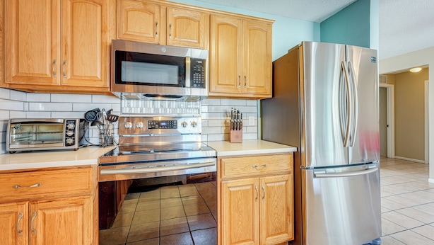 A kitchen with wooden cabinets, stainless steel appliances, and a tiled floor. - Fire Pit! Family Getaway, 6 Mi to Beach Access (Largo)