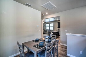 A dining area with a table set for four, a kitchen in the background, and a living area with a couch and a coffee table.