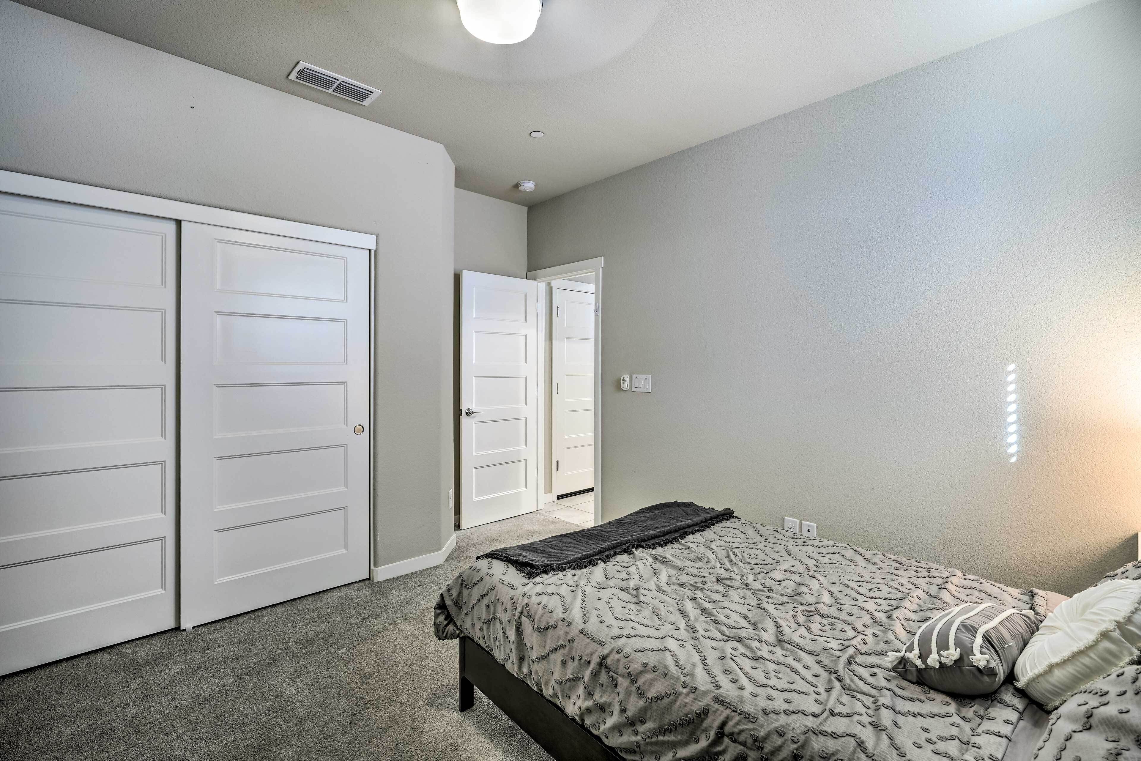 A bedroom with a bed, a closet, and a door leading to another room.