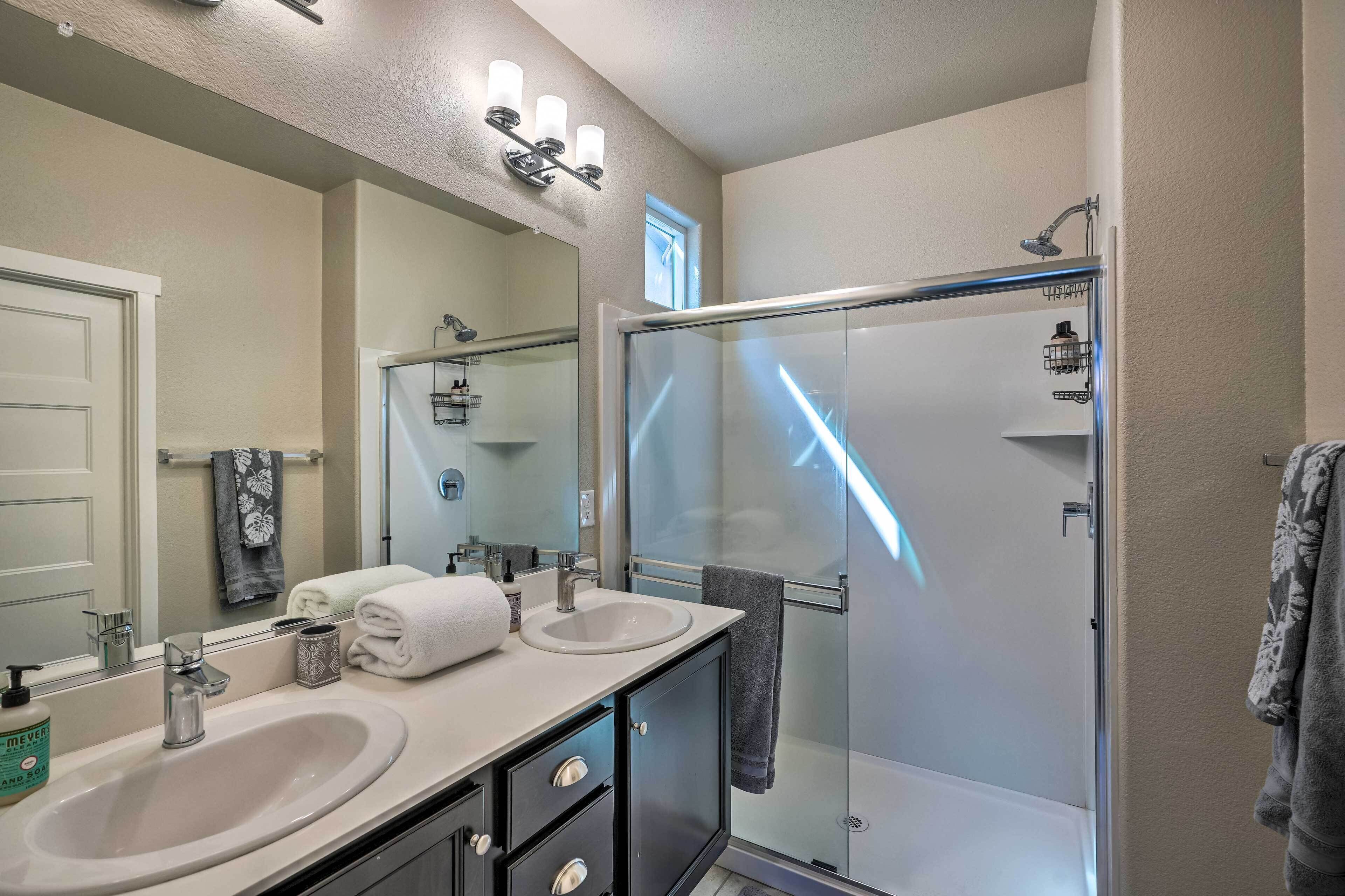 A modern bathroom with two sinks, a large mirror, and a glass-enclosed shower.