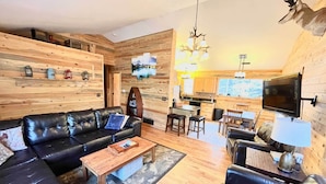 A modern living room with a black leather sofa, a wooden coffee table, and a TV mounted on the wall. - 'bobcat Trail Cabin' on 3 Acres in Como! (Como)