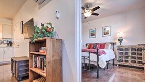 A bedroom with a bed, bedside table, lamp, and a view of the living area. - Quaint Kanab Casita - 3 Mi to the Heart of Town! (Kanab)