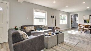 A modern living room with a grey sofa set, a coffee table, and a dining area with wooden chairs and a table. - Dtwn Winter Garden Home: 12 Mi to Disney! (Winter Garden)