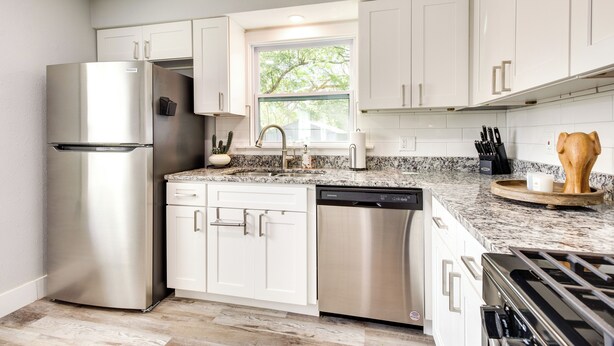 A modern kitchen with white cabinets, stainless steel appliances, a granite countertop, and a window providing natural light. - Dtwn Winter Garden Home: 12 Mi to Disney! (Winter Garden)