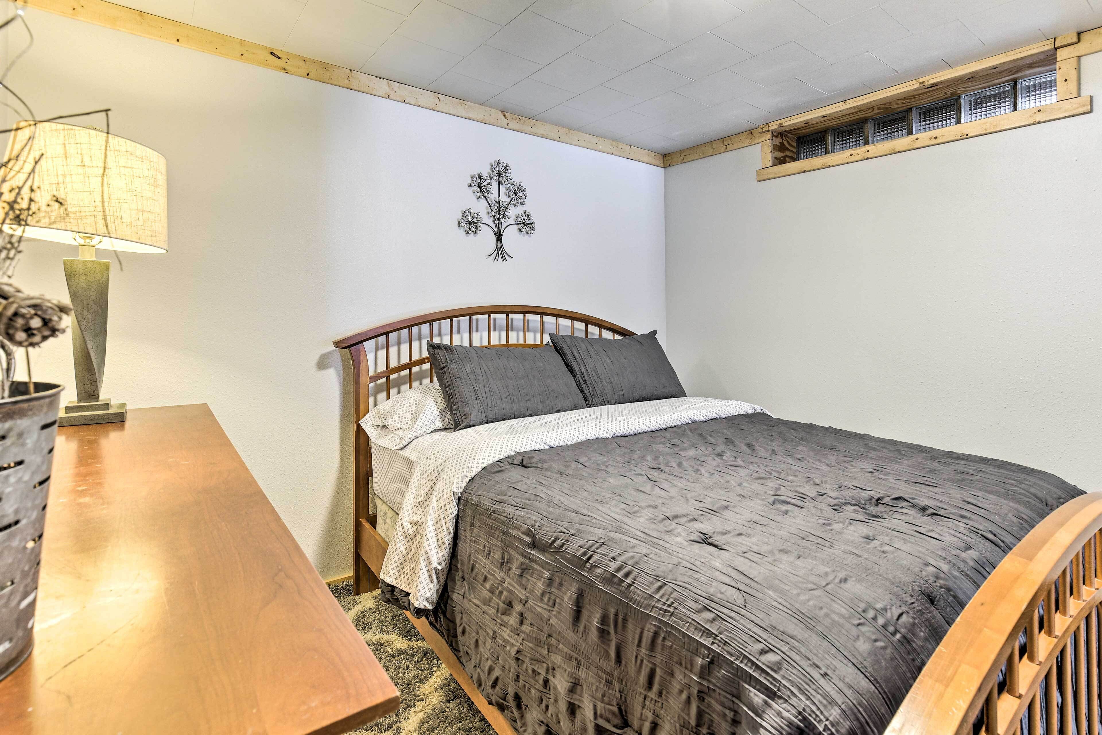 A bedroom with a wooden bed, a nightstand, a lamp, and a wall decoration.