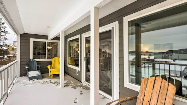 Un balcon abrité offrant une vue sur un paysage enneigé, avec une chaise en bois et une chaise jaune.