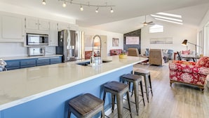 Une cuisine moderne dotée d’un îlot central, de tabourets de bar et d’un coin repas avec un canapé rouge à motifs floraux.