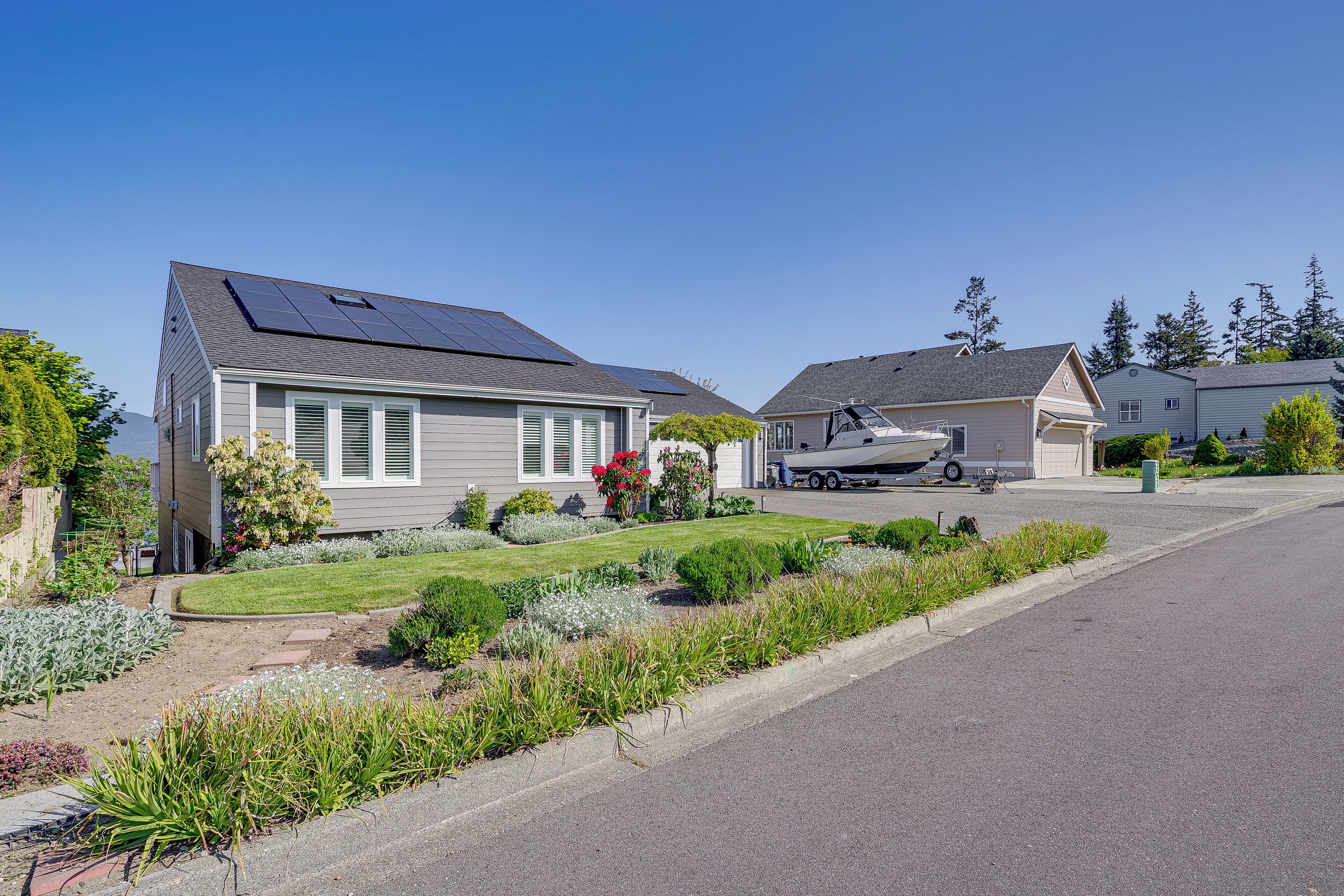 Una calle residencial con casas, paneles solares y un jardín bien cuidado.