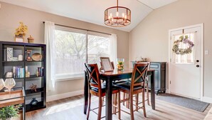 A dining area with a wooden table and chairs, a bookshelf, and a chandelier. - Airy Georgetown Home w/ Fire Pit! (Georgetown)