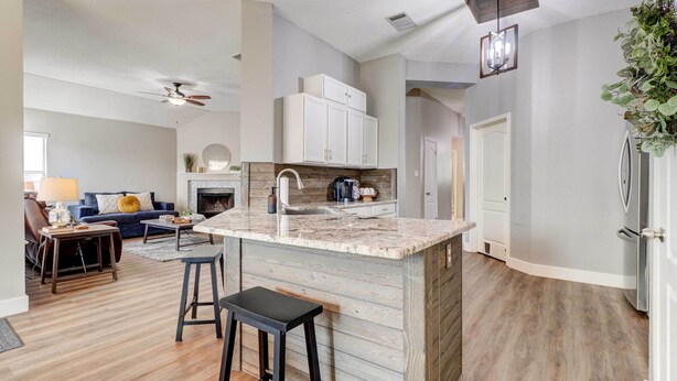 A modern kitchen with a central island, wooden flooring, and white cabinetry. - Airy Georgetown Home w/ Fire Pit! (Georgetown)