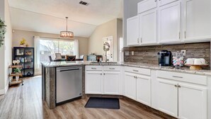 A modern kitchen with white cabinets, a built-in dishwasher, and a stone backsplash. - Airy Georgetown Home w/ Fire Pit! (Georgetown)