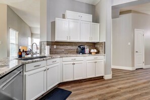 Una cocina con armarios blancos, encimera de granito y protector de salpicadero de madera.